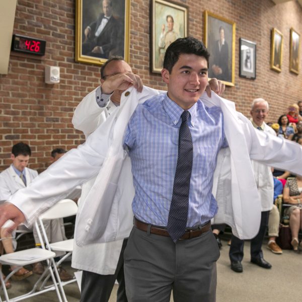 A man puts on a white coat