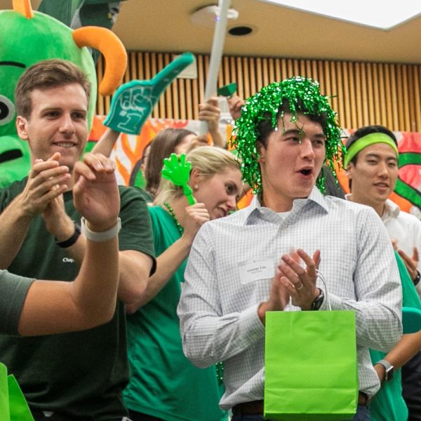 Students in green clothing and spirit wear yell and clap