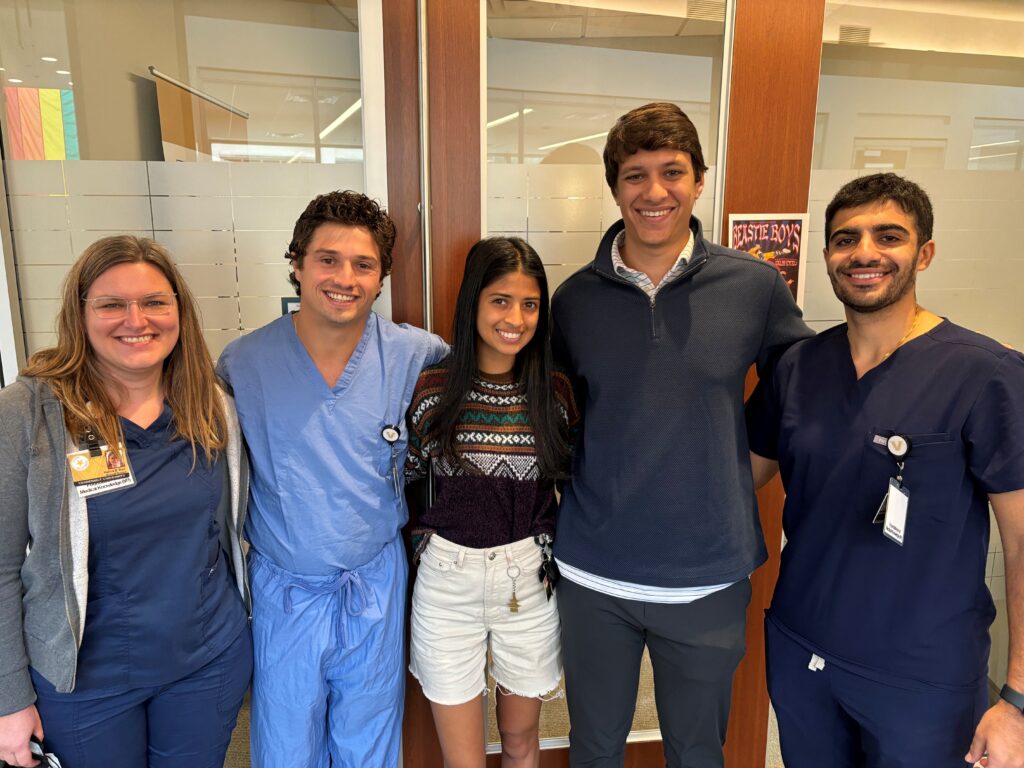 A group of five smiling VUSM students and clinicians pose for a photo in a hallway.